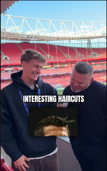 Two men at a stadium looking at a picture of a man's unusual haircut.