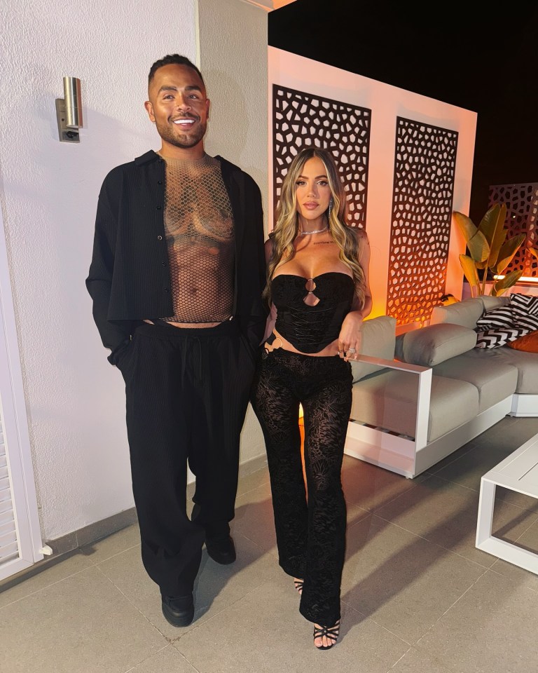 Photo of a man and woman posing together outdoors at night.