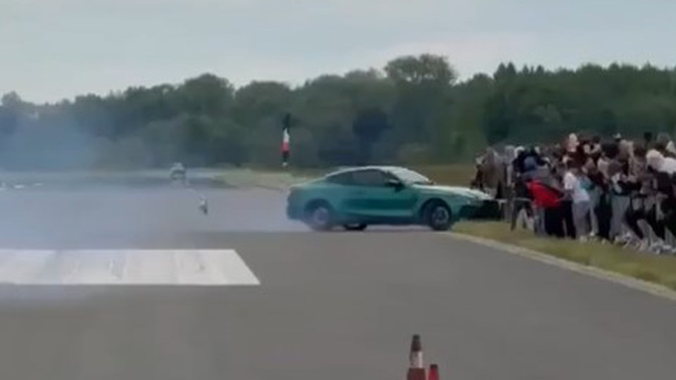 Green sports car doing a burnout with spectators watching.