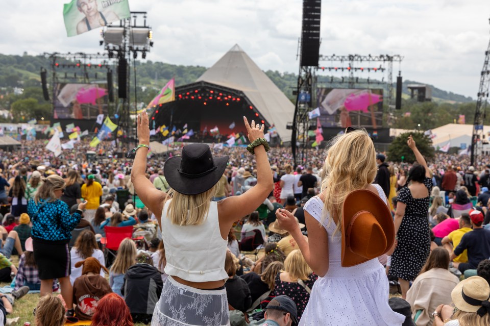Concertgoers at Glastonbury Festival with the Pyramid Stage in the background.