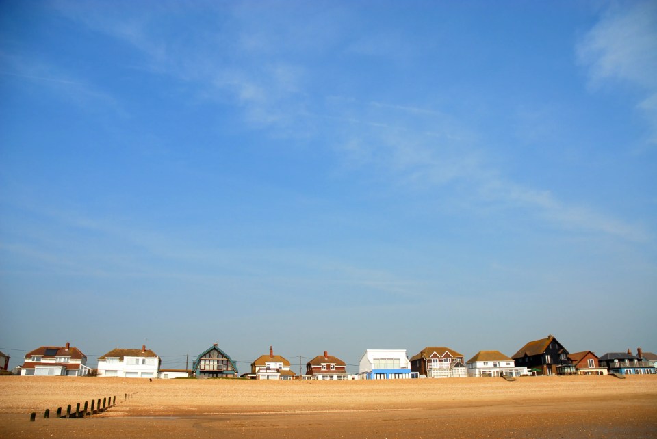 Houses on a beach under a blue sky.