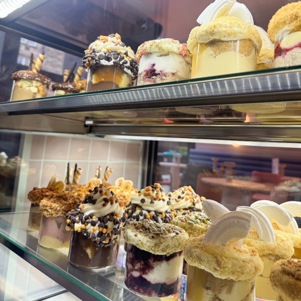 Assortment of desserts in glass jars displayed in a shop.