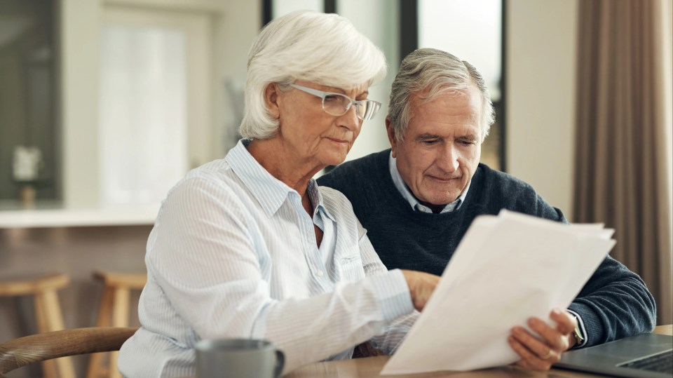 a man and woman sit at a table looking at a piece of paper