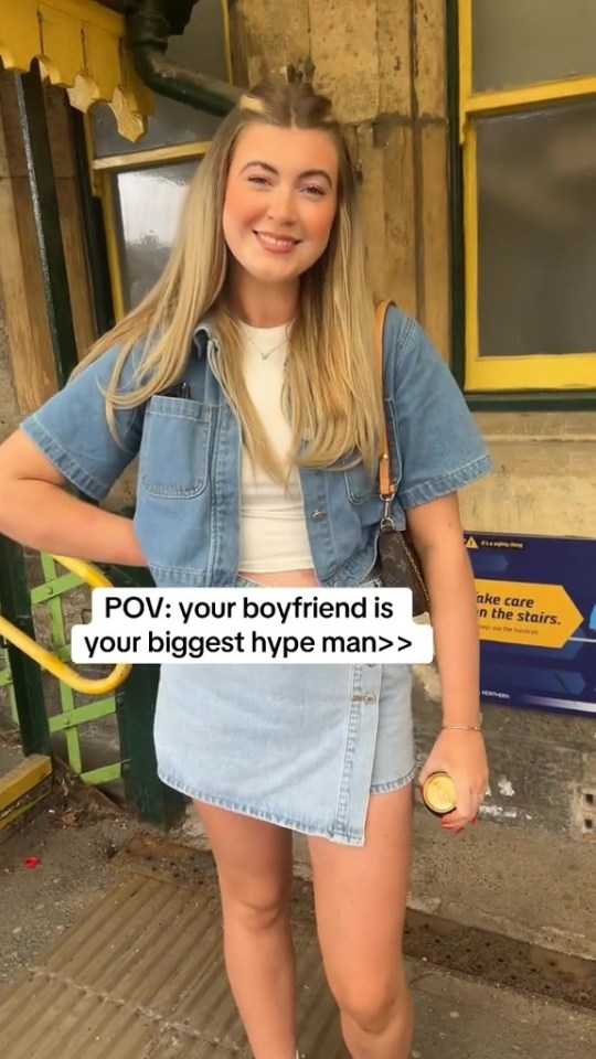 Woman in denim outfit at a train station.