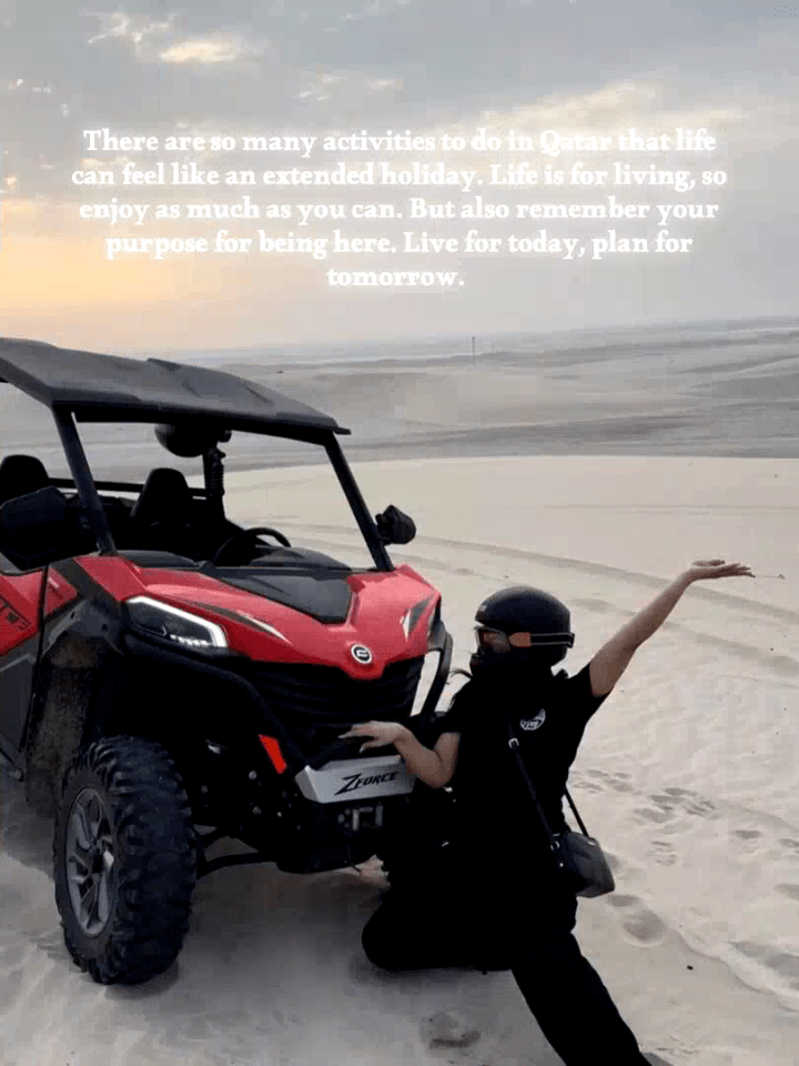 Woman posing next to a red ATV in a desert.