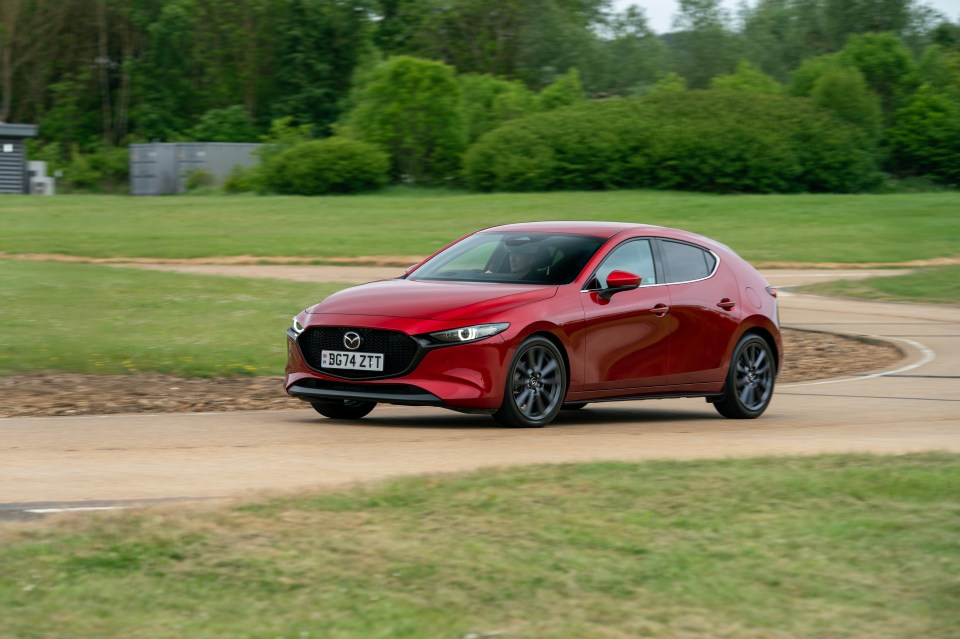 Red Mazda driving on a track.