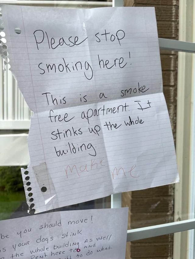 Handwritten notes on a window complaining about smoking and dog odor in an apartment building.