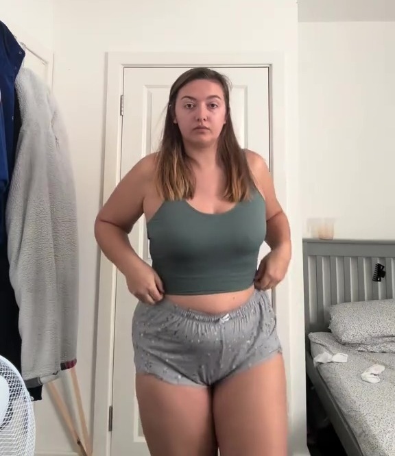 Woman in green top and gray shorts.