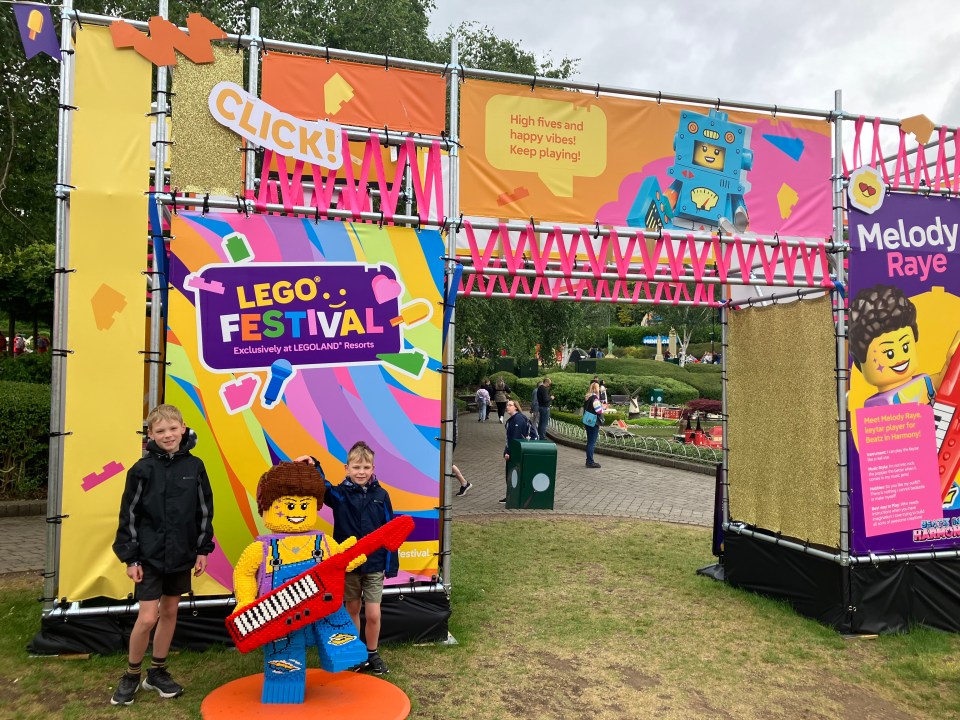 Two boys posing with a large Lego figure at the Legoland Festival.