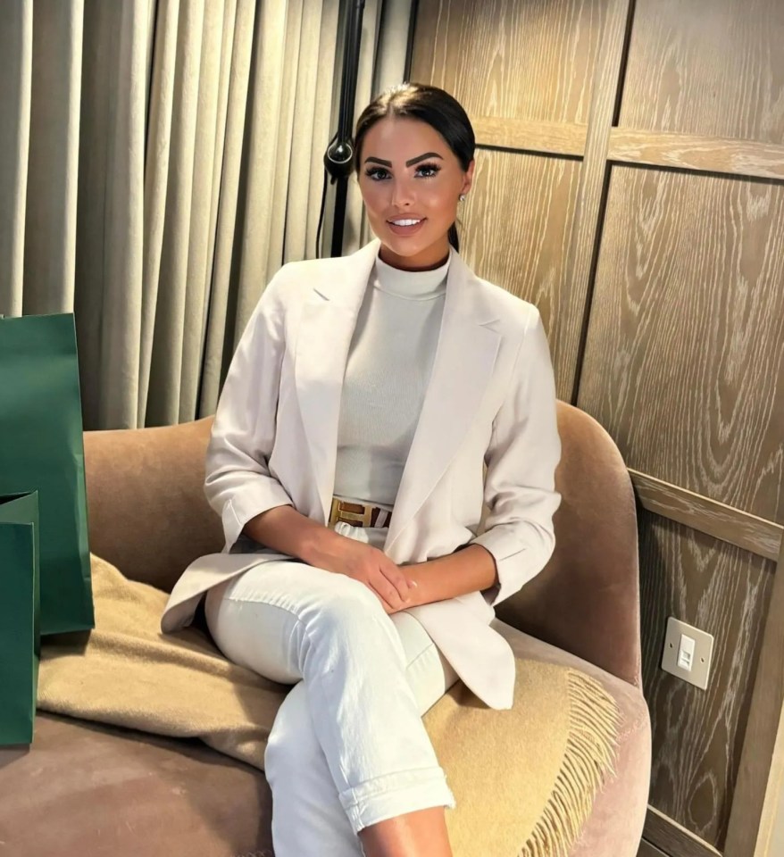 a woman sits on a couch next to a harrods bag