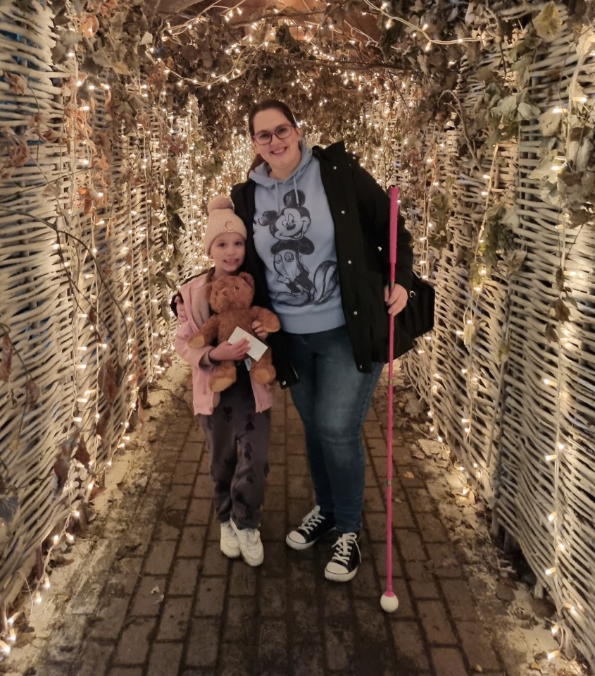 A woman and child stand in a lighted walkway.