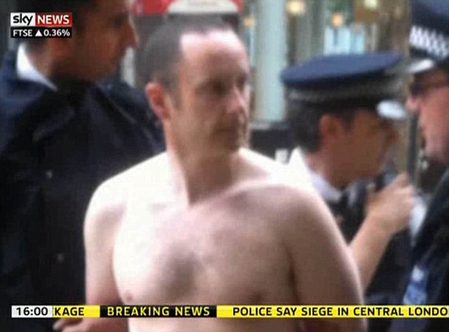 A shirtless man being led away by police.