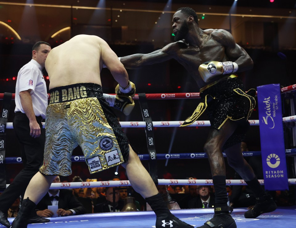Zhilei Zhang (gold shorts) and Deontay Wilder (black shorts) boxing.