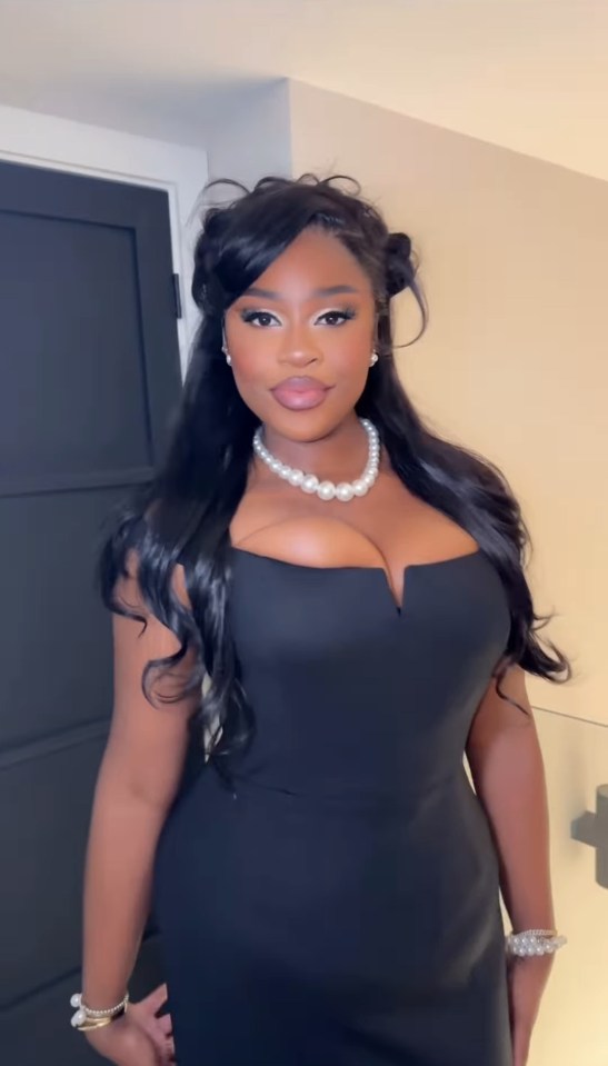 Nella Rose in a black dress and pearl necklace.