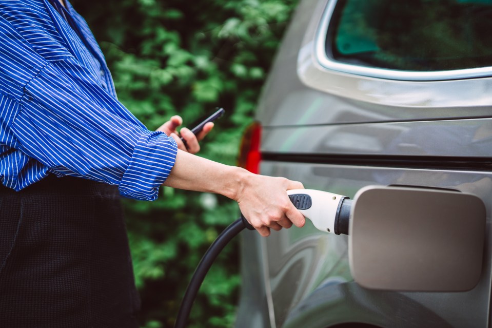 A businesswoman charging an electric car.
