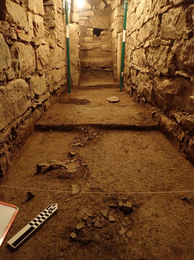 Excavated interior of a stone structure at Chavín de Huantar, Peru, showing artifacts and soil layers.