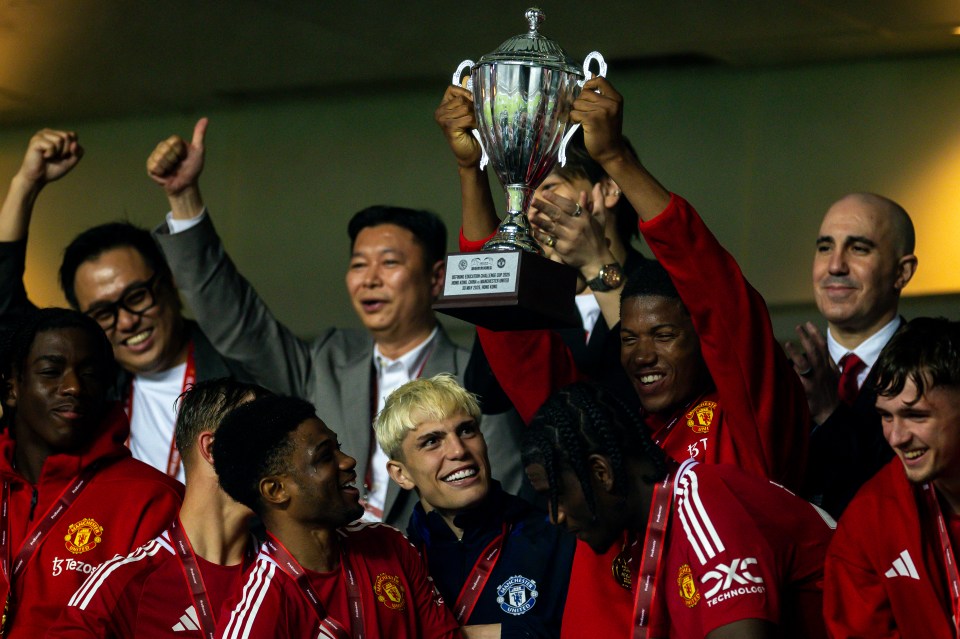 Manchester United players celebrating with a trophy.