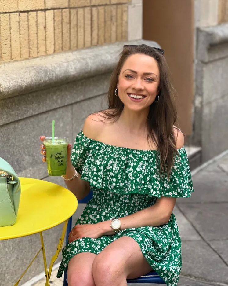 Woman in green floral dress holding a matcha latte.