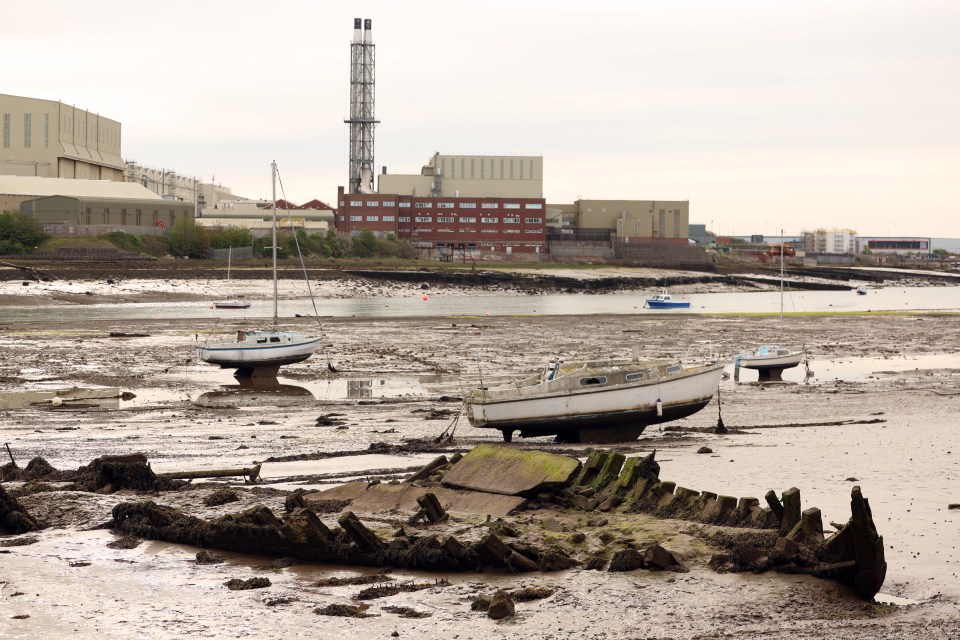 Barrow Island, Cumbria: boats on mudflats with a shipwreck and industrial buildings in the background.