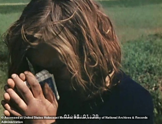 The woman, who is holding what appears to be a pack of cards, looks as though she is going to cry as the camera continues focusing on her
