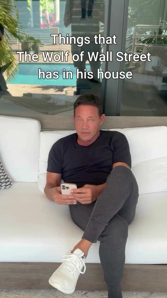 Jordan Belfort in his home, looking at his phone.