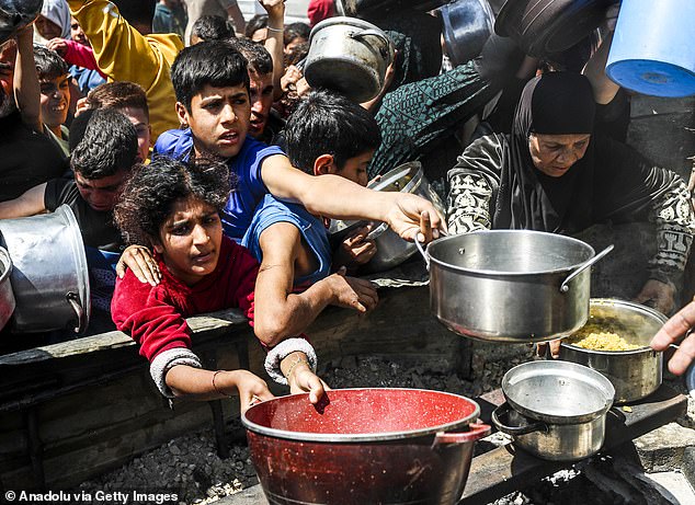Displaced Palestinians receive hot meals distributed by aid organizations in Jabalia refugee camp of Jabalia, Gaza on May 5, 2025