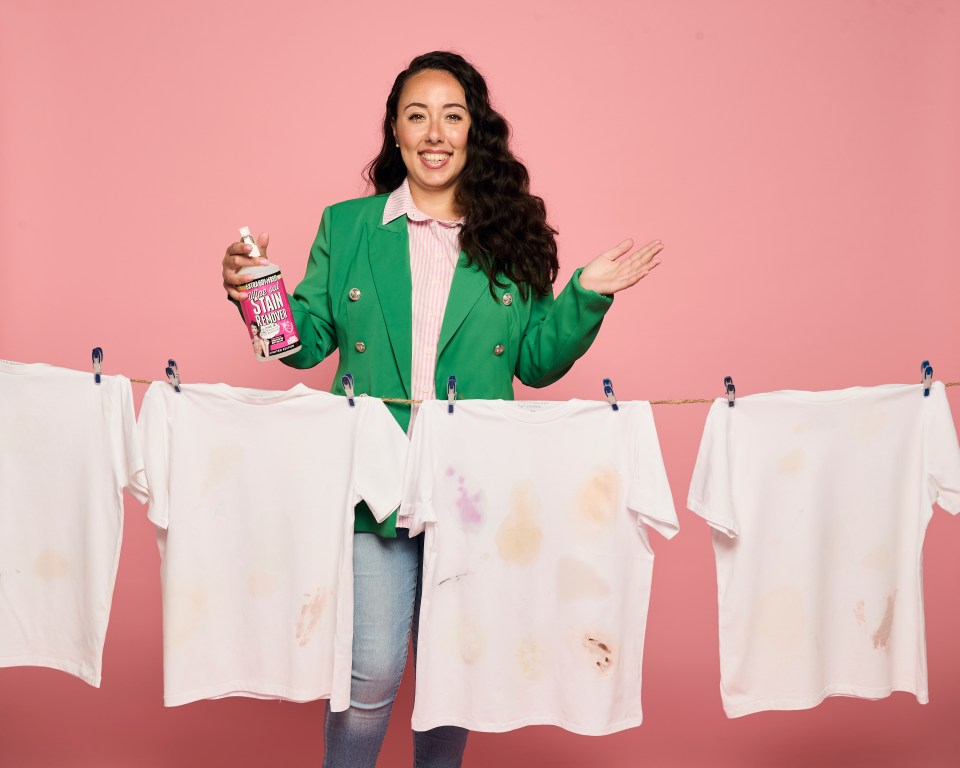 Woman holding stain remover and showing stained shirts.