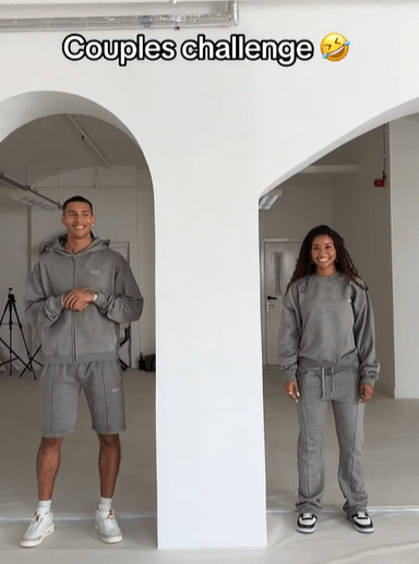 Couple in matching gray sweatsuits participating in a couples challenge.