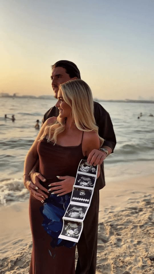 Pregnant Claudia Fogarty and Ollie Crankshaw on a beach holding ultrasound images.