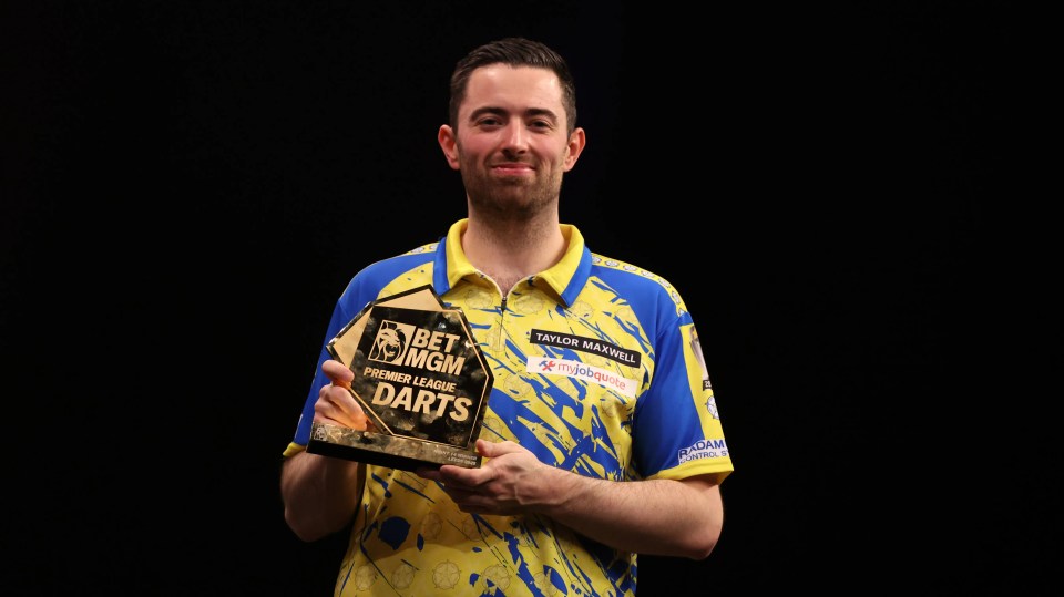 Luke Humphries holding the BetMGM Premier League Darts trophy.