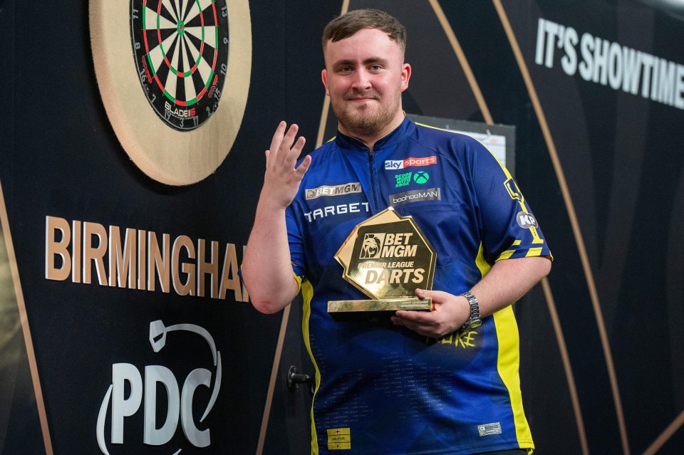 Luke Littler holding a Premier League Darts trophy.