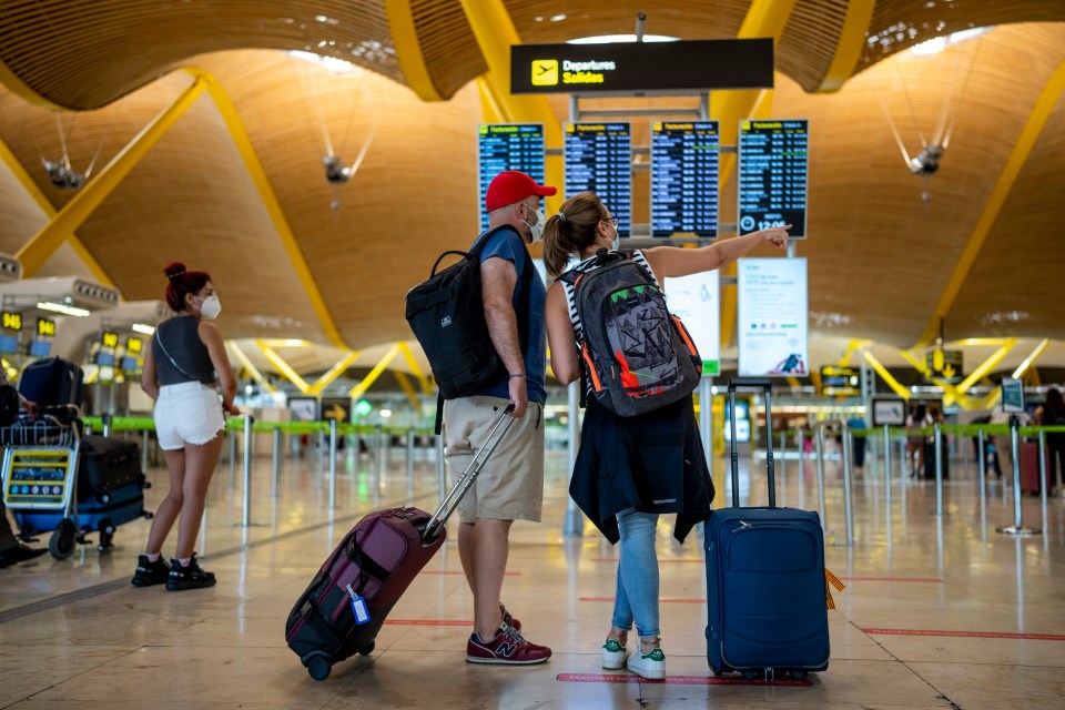Couple checking departures board at Madrid airport.