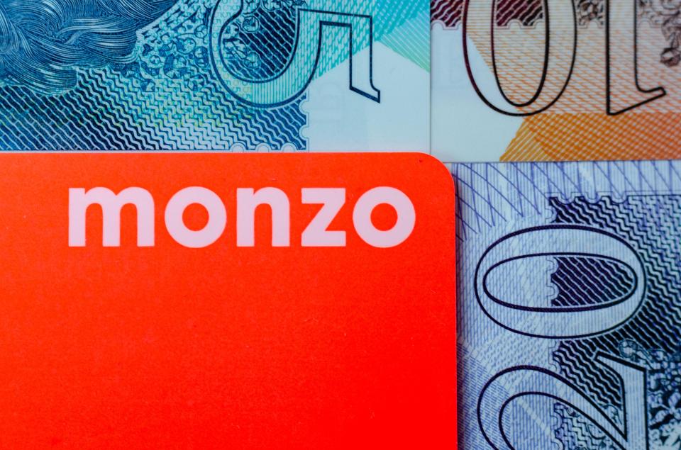 Monzo bank card against British pound banknotes.