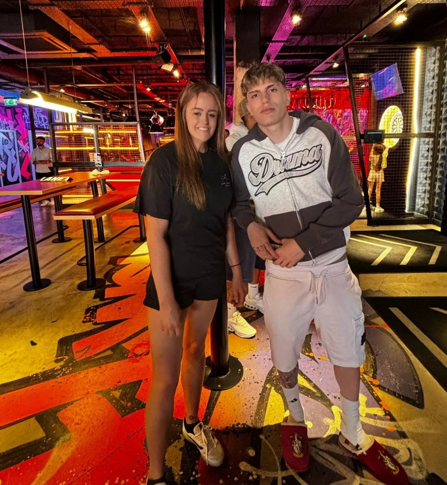 Two young people posing in a brightly lit arcade.