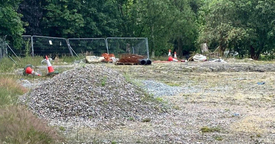 Construction site with gravel piles, traffic cones, and construction materials.