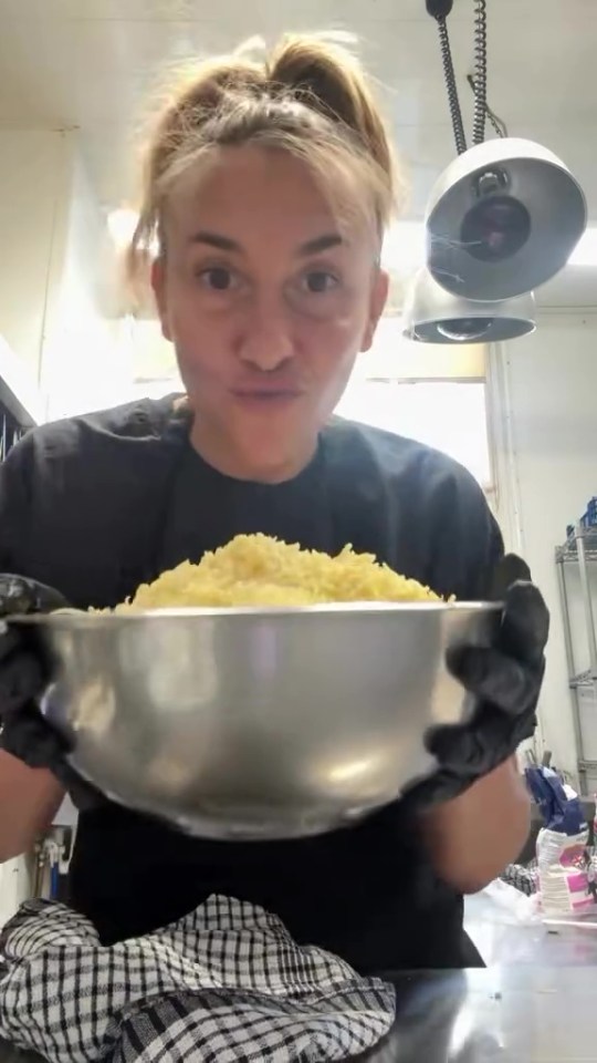 A woman holds a large bowl of food.