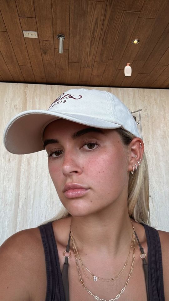 Woman wearing a baseball cap and necklaces.