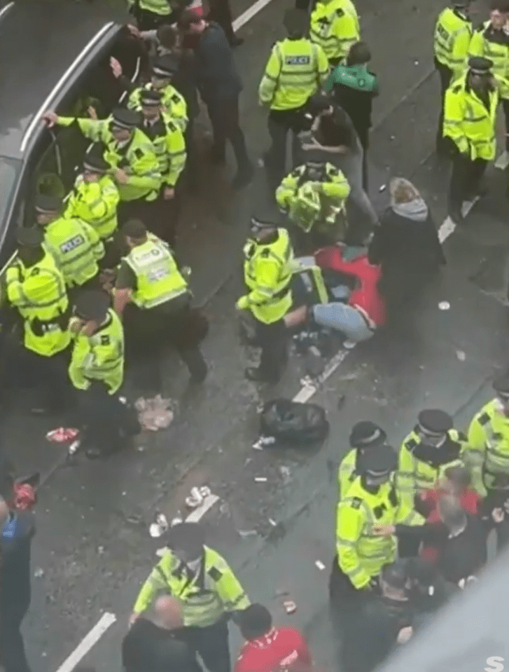 Police officers arresting a person on the ground amidst a crowd.