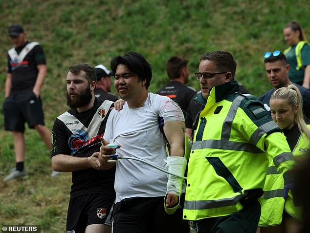 A man is helped by a rugby player and medic after injuring himself during the race on Monday