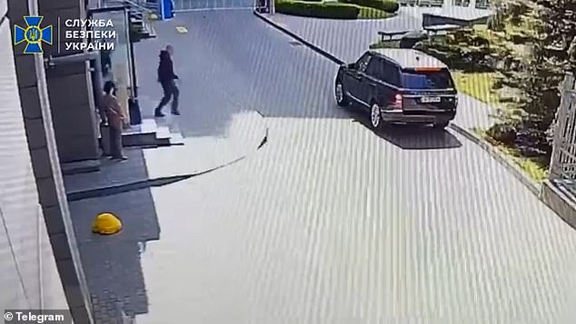 Harrowing footage taken by CCTV shows a woman standing outside a residential building as the activist walks towards his car