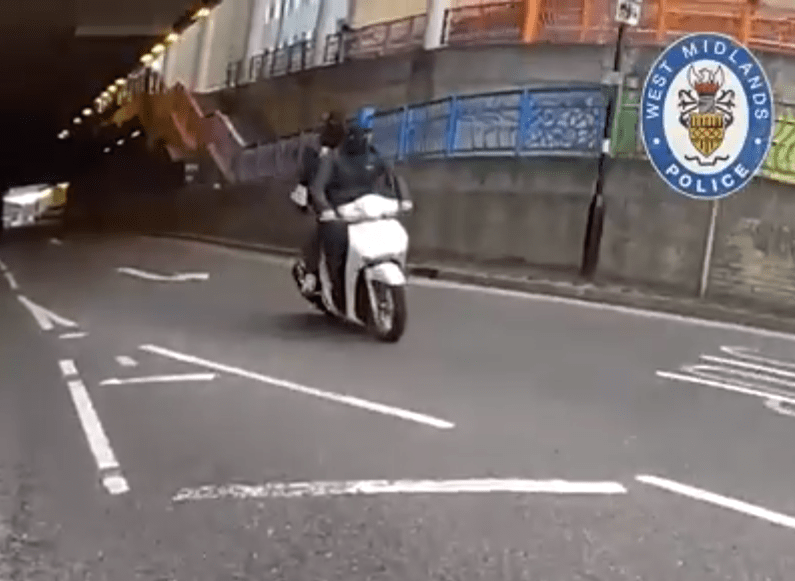 Person on a white scooter driving through a tunnel.