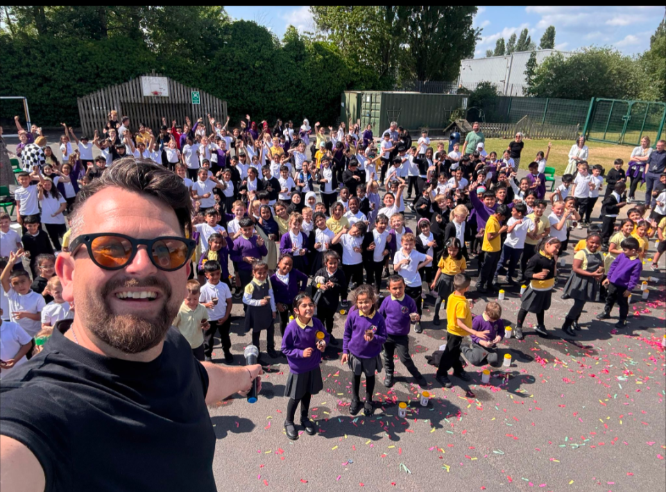 A man taking a selfie with a large group of schoolchildren.