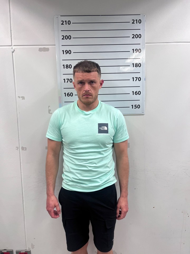 Mugshot of a man in a mint green shirt and black shorts.