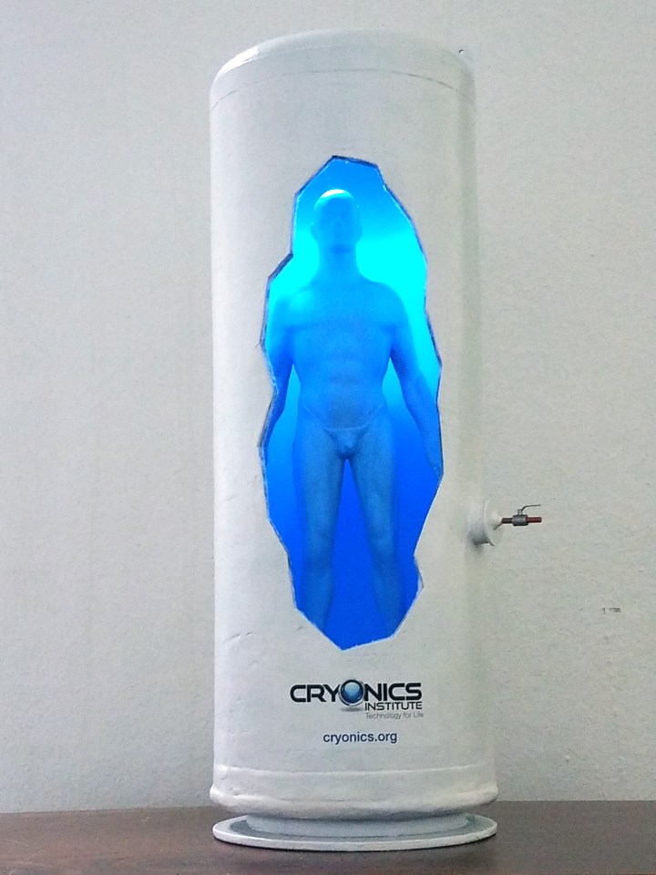 Model of a cryonics institute cryogenic chamber with a human figure inside.