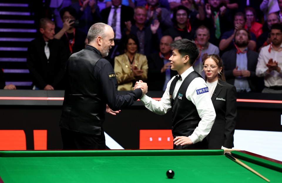 Zhao Xintong of China and Mark Williams of Wales shaking hands after a snooker match.