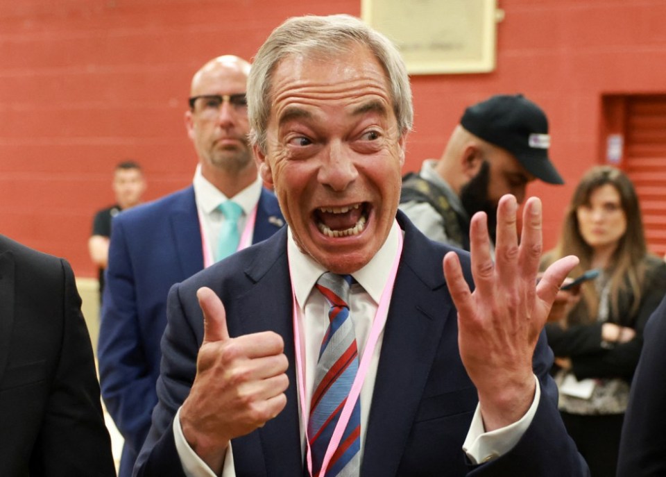 Nigel Farage giving a thumbs-up and raising his other hand.