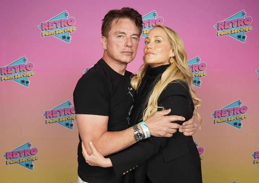 John Barrowman and Elizabeth Berkley embracing.