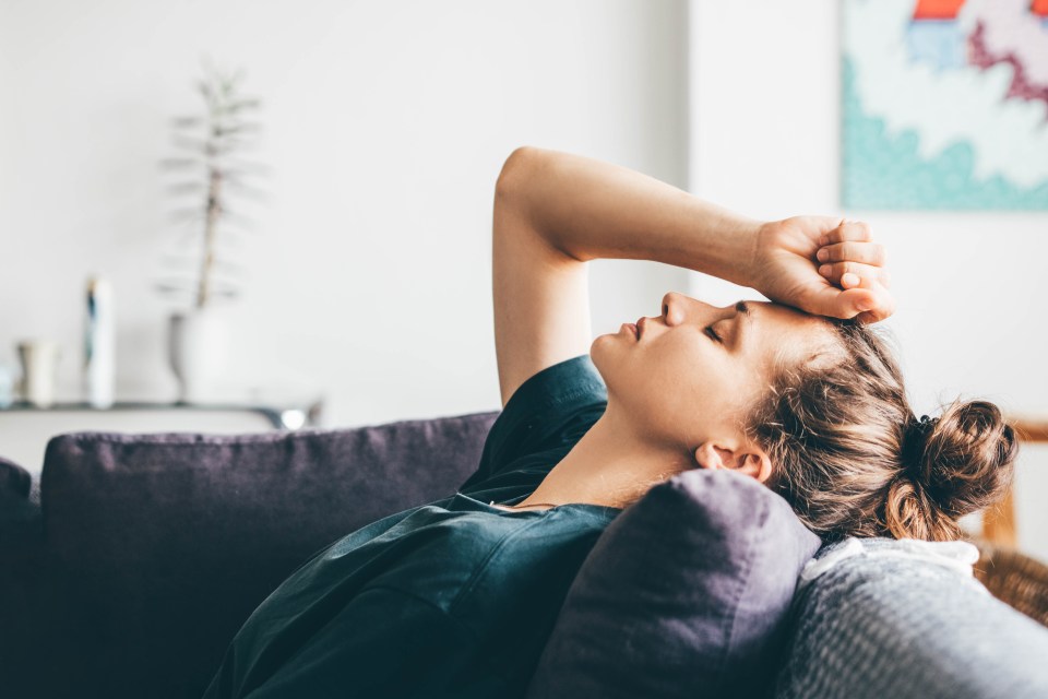 Woman sitting on a couch looking sad.