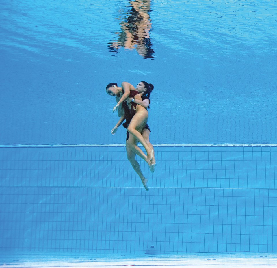 Two synchronized swimmers underwater.
