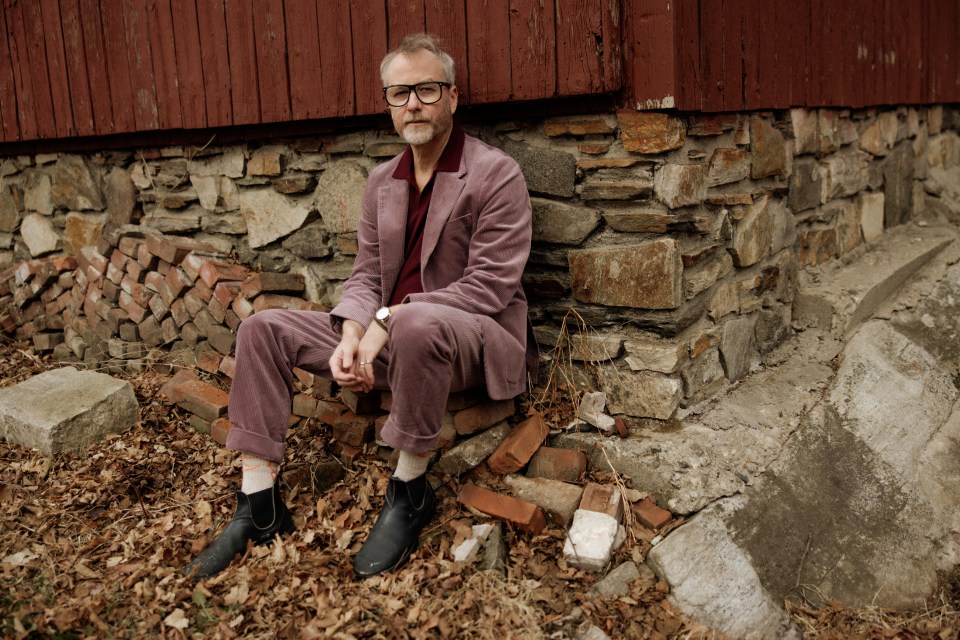 Matt Berninger sitting against a stone wall.